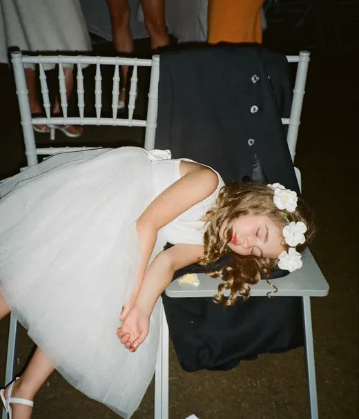 Flower girl asleep on a chair in her white dress