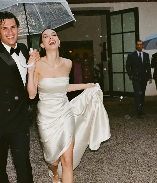 Couple laughing under a clear umbrella on a rainy exit