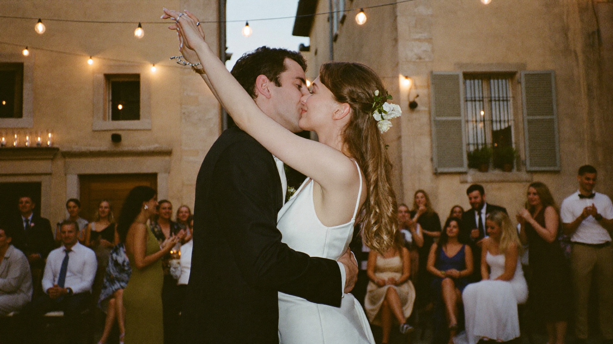 A candid first-dance kiss at a Tuscan wedding under string lights