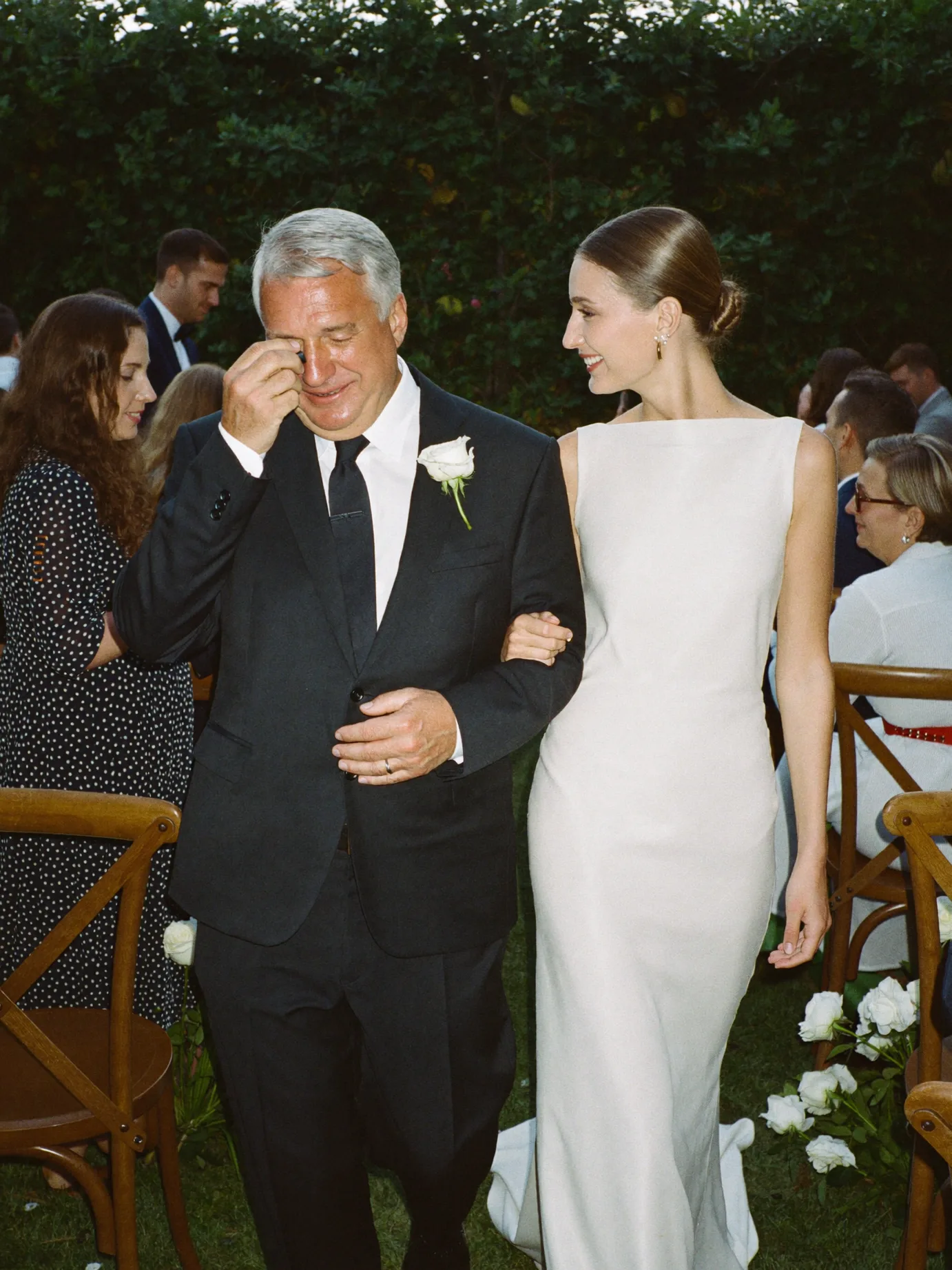A father wiping a tear as he walks his daughter down the aisle